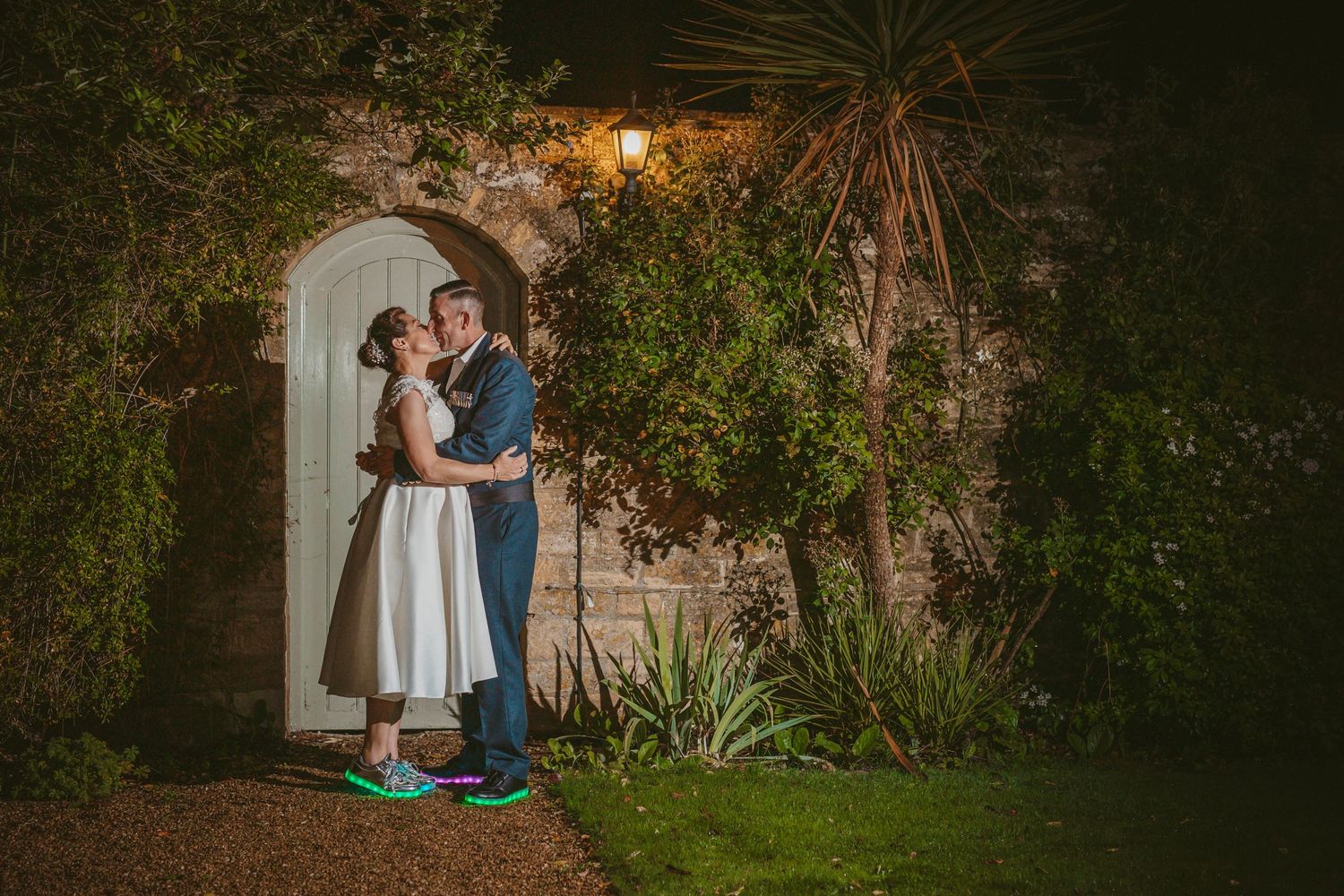 A couple shares an intimate moment beneath an arched garden doorway at twilight.