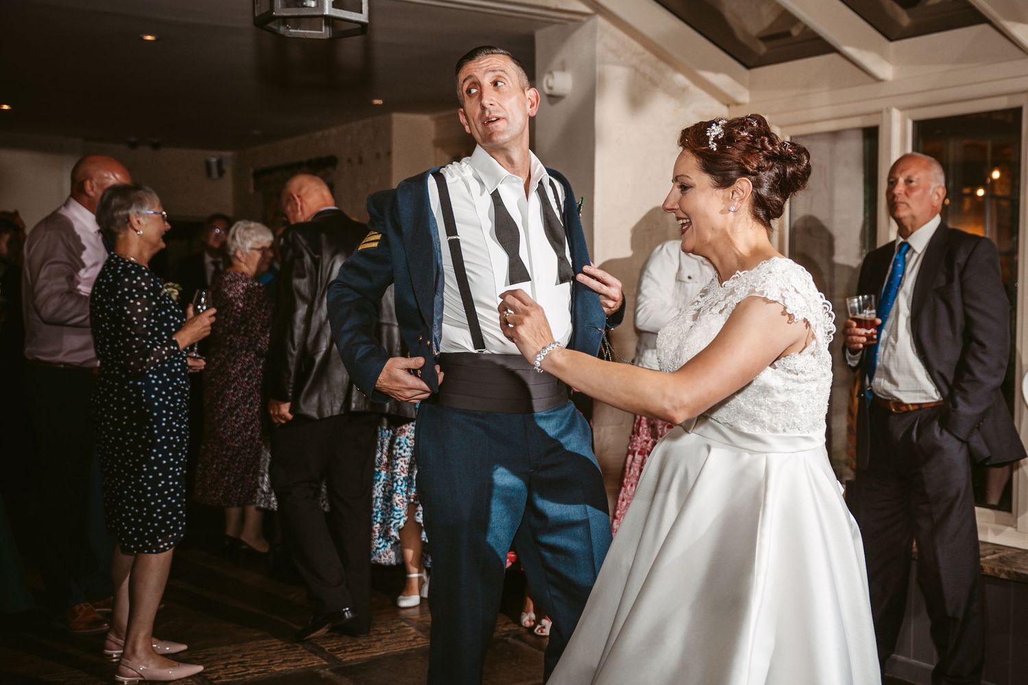 Dancing couple shares a lively moment at their wedding reception while guests watch.