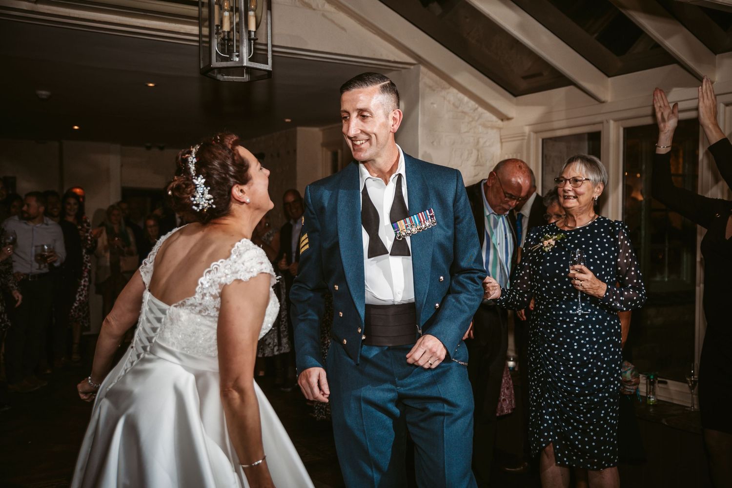 A couple shares a joyful moment on the dance floor at their wedding reception in an elegantly lit venue.