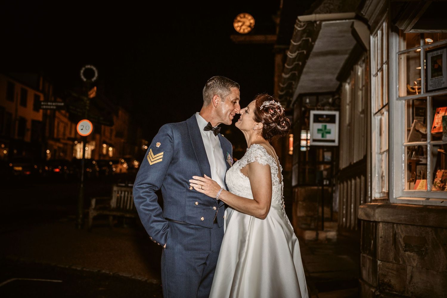 Romantic evening portrait of couple on cobblestone street with city lights.