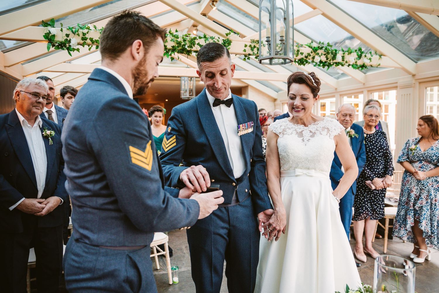 Wedding celebration in a conservatory with guests gathering around for a special moment.