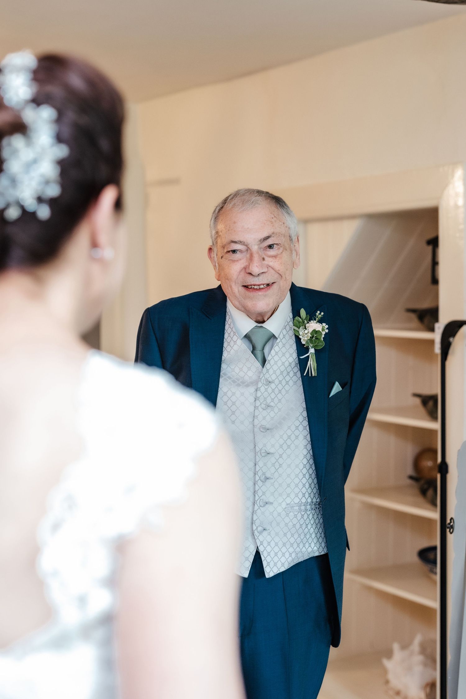 A touching wedding day moment captured in an indoor setting with formal attire.