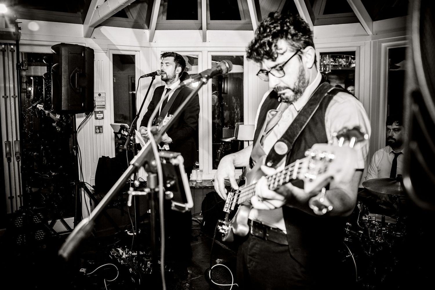 Black and white photo of musicians performing with guitars at a wedding reception.