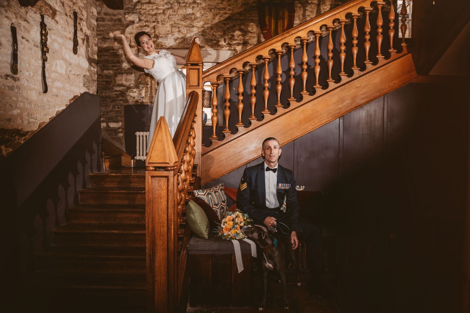 A dramatic wedding portrait on a vintage wooden staircase with moody lighting and stone walls.