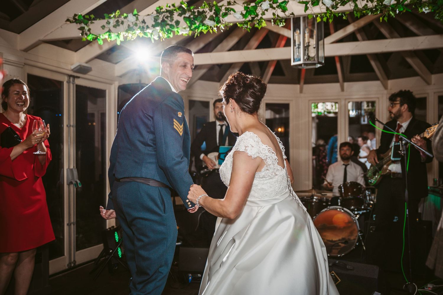 Couple dances under greenery-decorated beams at their evening wedding reception.