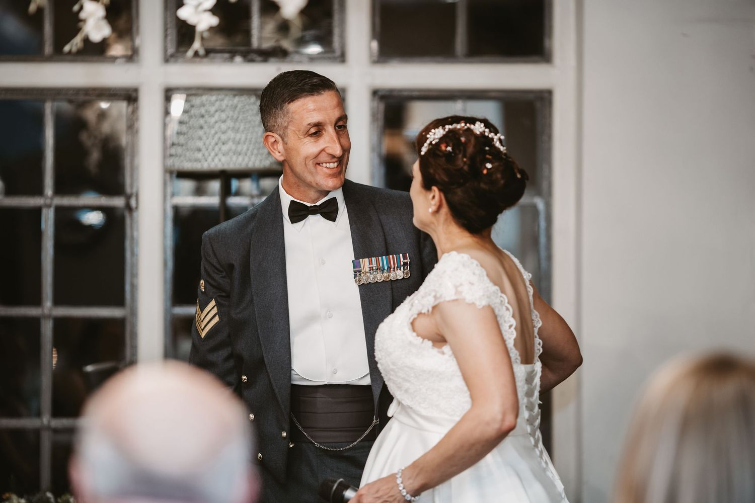 Military serviceman and bride share a joyful moment during their wedding ceremony.