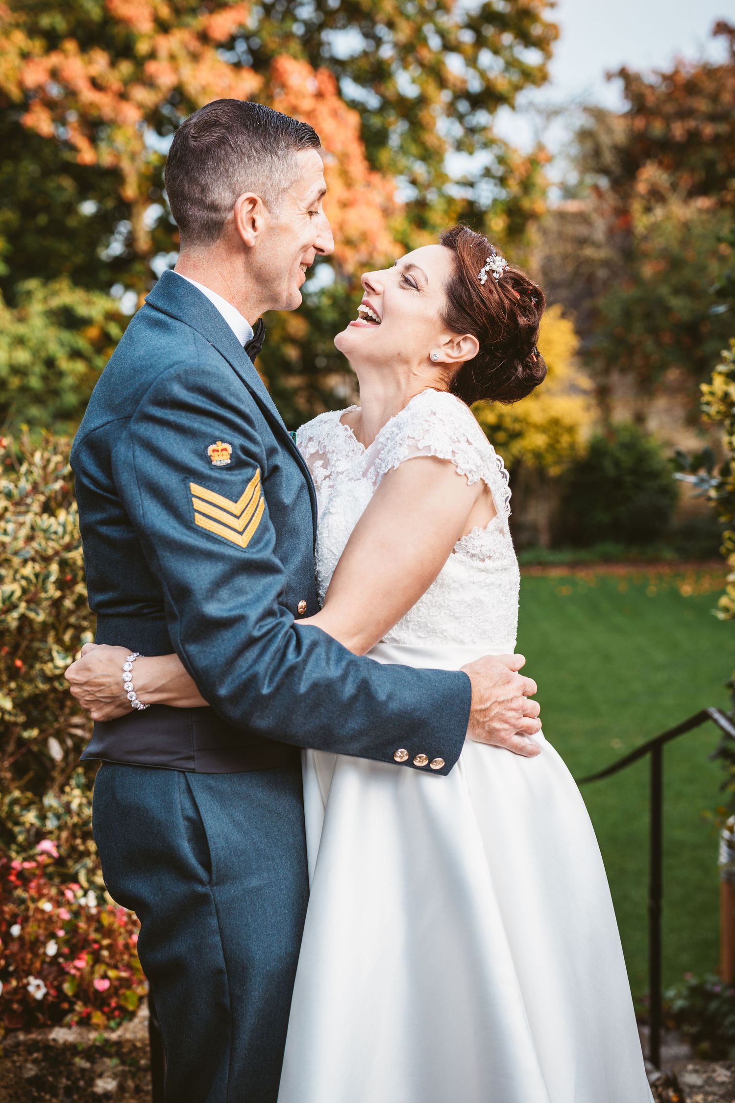 Happy wedding couple laughing together in garden with fall foliage.