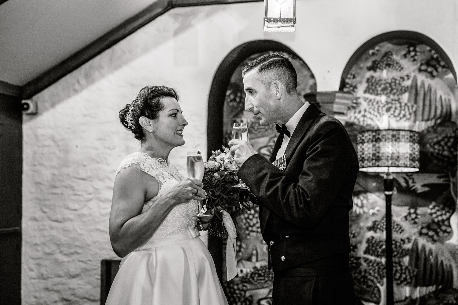 A black and white wedding photograph captures a tender moment during the ceremony.