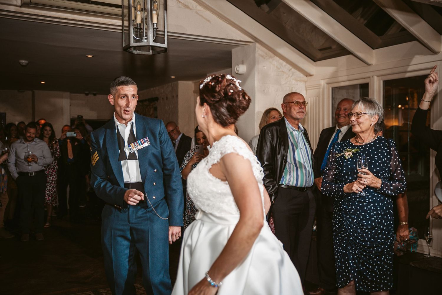 Newlyweds share a playful dance moment in a beautifully decorated indoor venue with exposed beams.