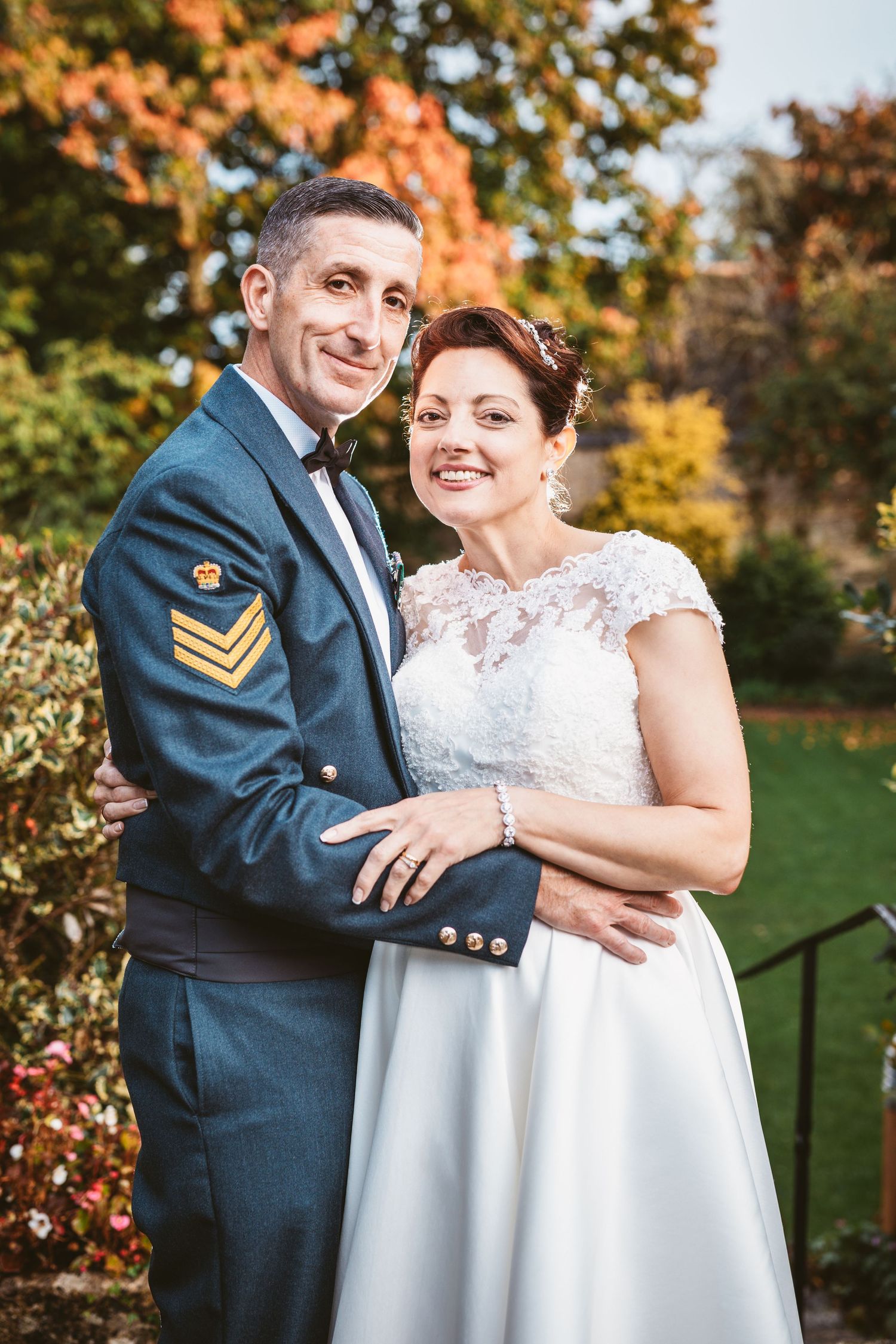 Military couple poses for wedding portrait in garden with beautiful fall colors.