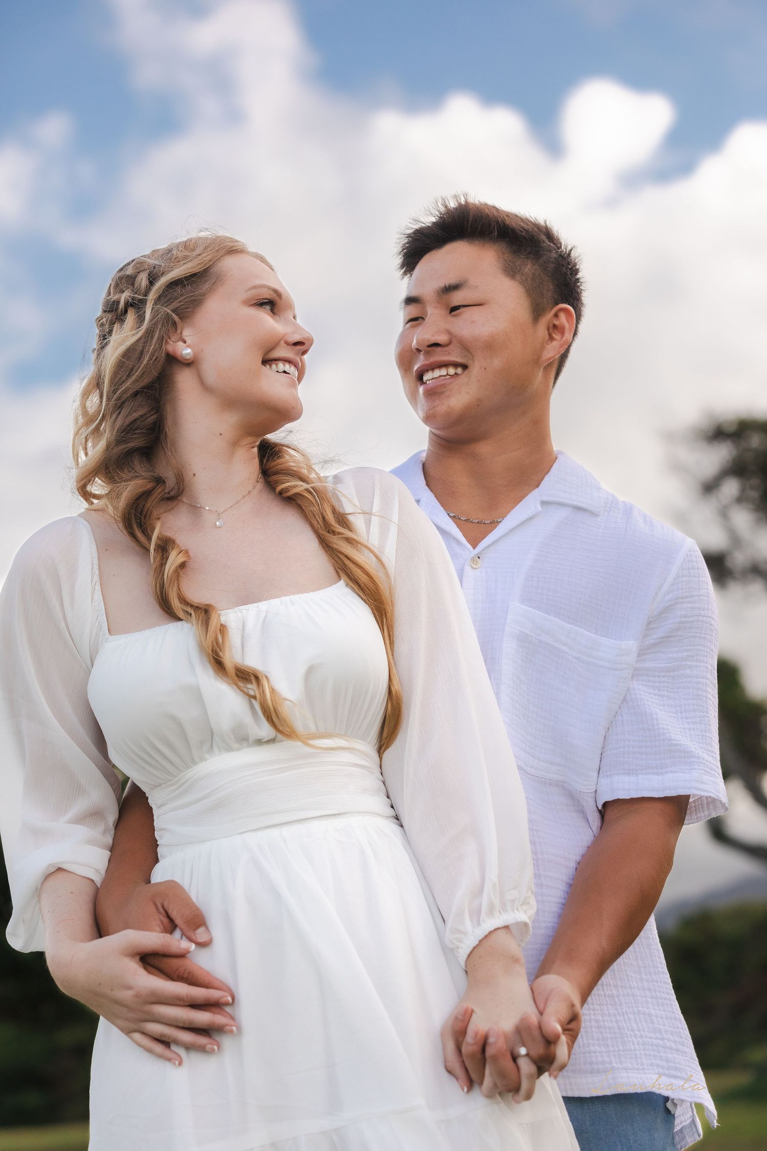 A happy couple shares a loving moment against a bright blue sky.