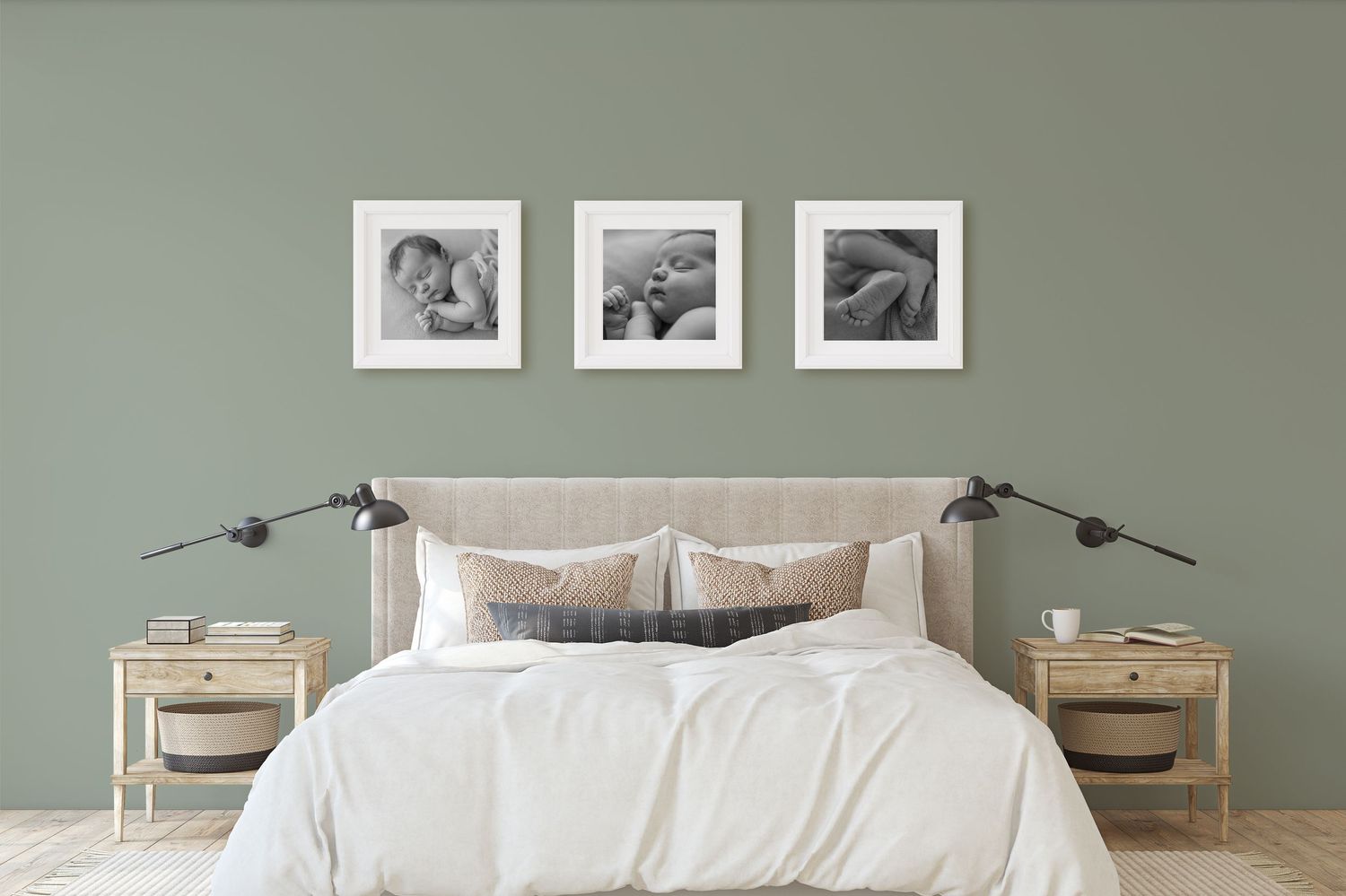 Three framed black and white newborn photos displayed above a bed on a sage green wall.
