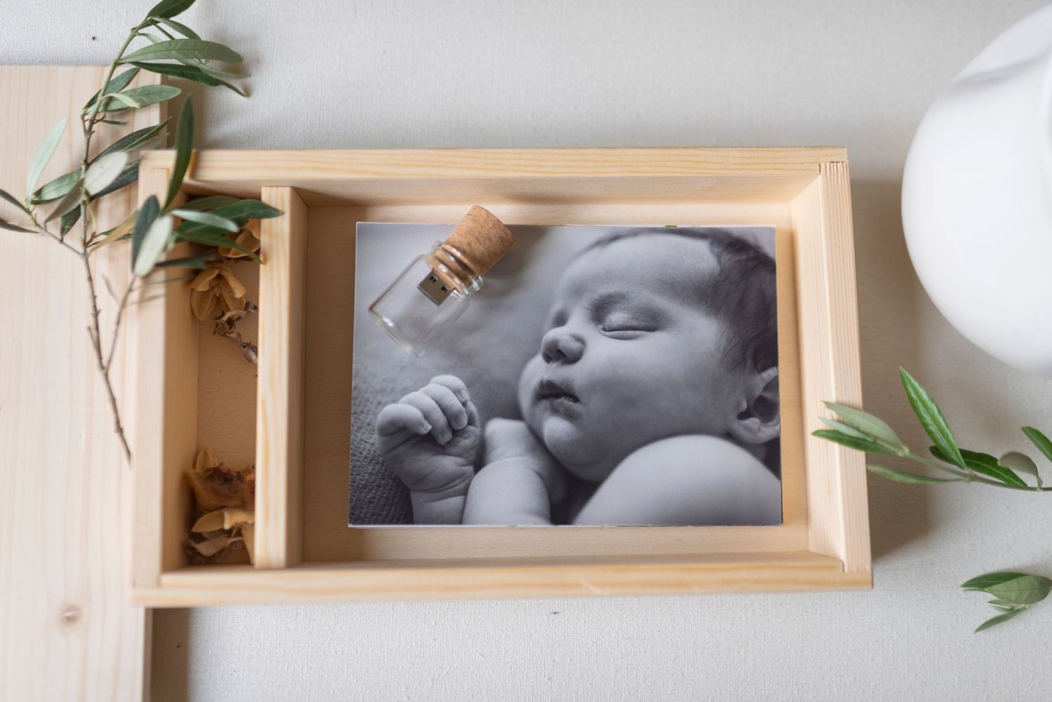 Black and white newborn baby photo print in a rustic wooden shadow box frame with botanicals.