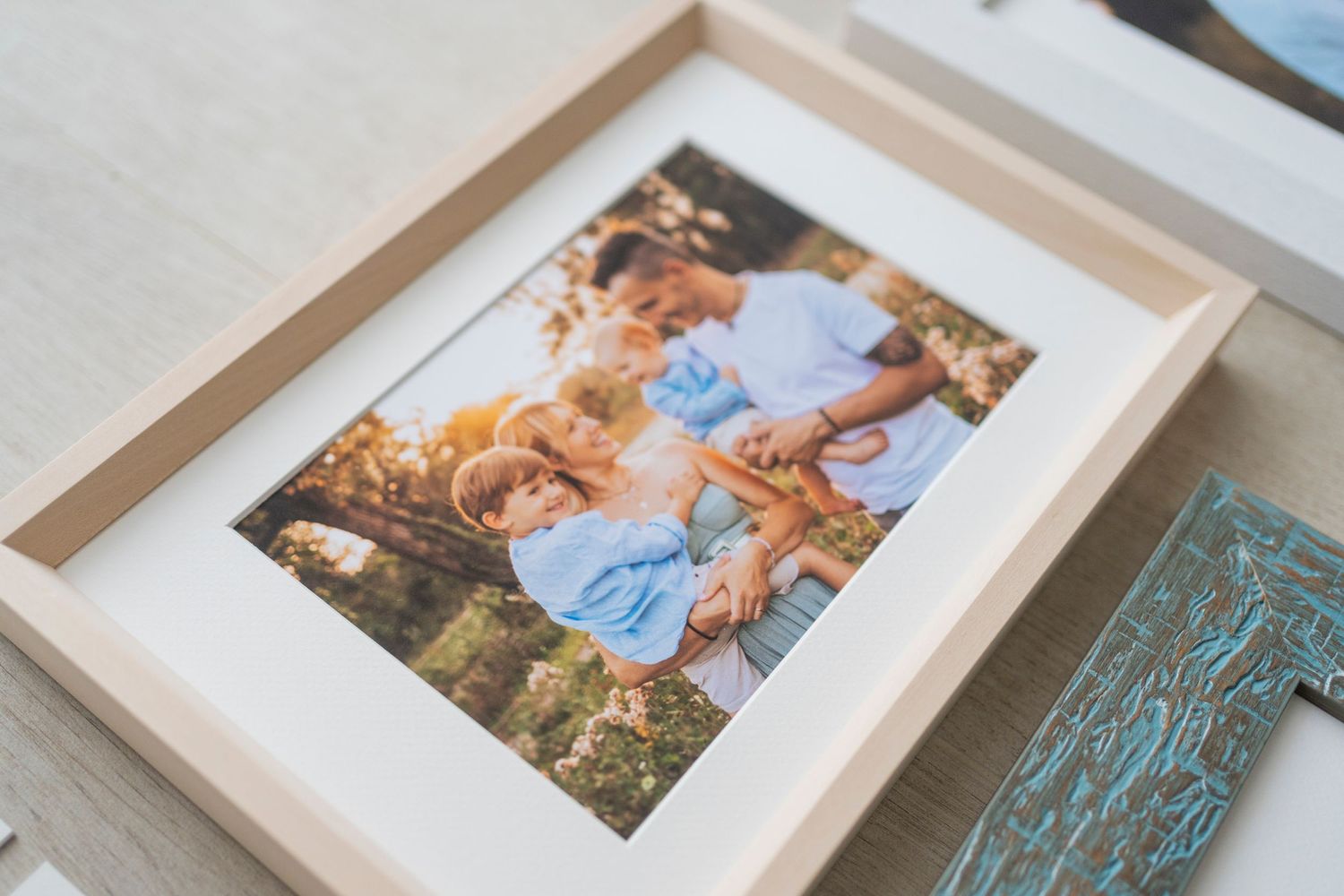 Family portrait photo print displayed in a natural wood frame with white mat on a table.