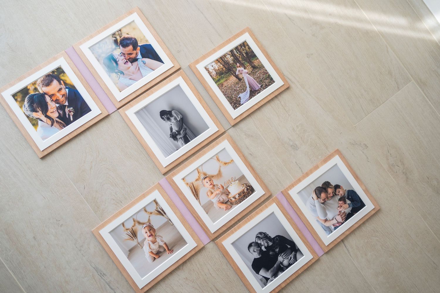 Collection of framed family and newborn photos arranged on light wooden floor.