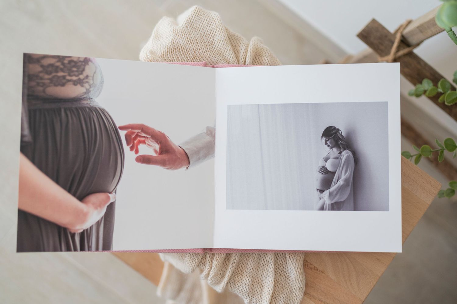 Open maternity photo album showing black and white pregnancy portraits on wooden table.