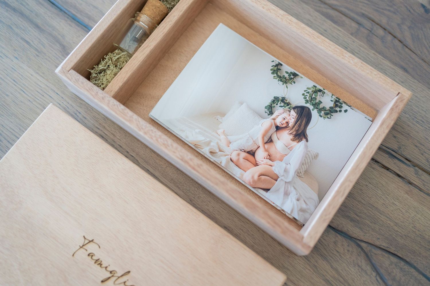 Wooden keepsake box with family name engraved containing printed newborn photos.