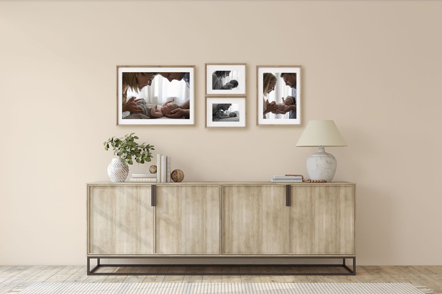 Three framed newborn portrait photos in warm tones displayed above a wooden sideboard.