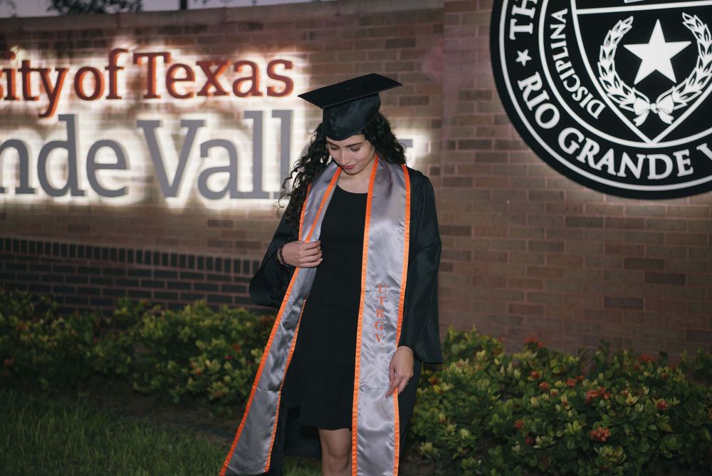 graduated girl looking down to her insignia. UTRGV session. Edinburg, Texas. wedding photography