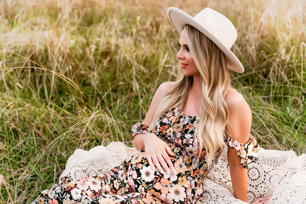 Sitting portrait of pregnant mom looking off in field