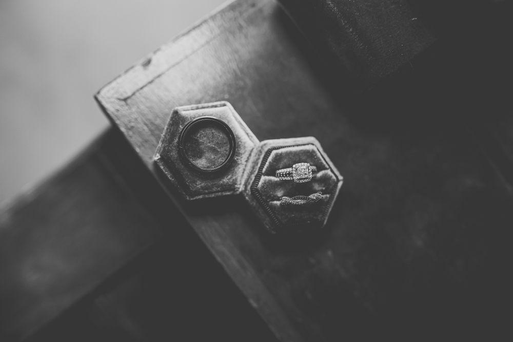 Close-up black and white photo of hexagonal wedding rings on a textured surface.