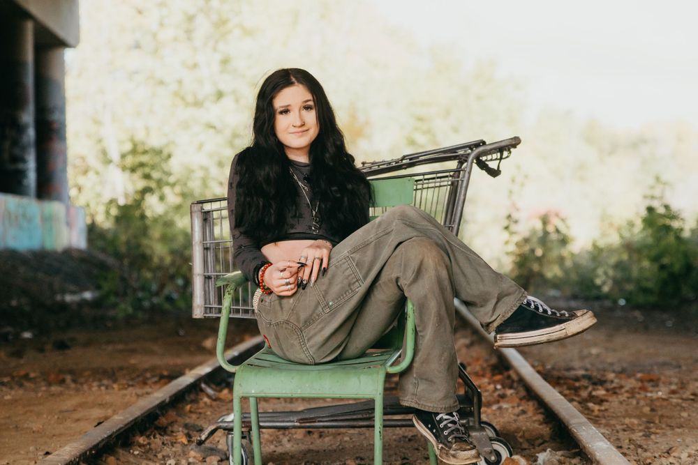 Casual portrait of someone relaxing in a vintage metal chair outdoors.