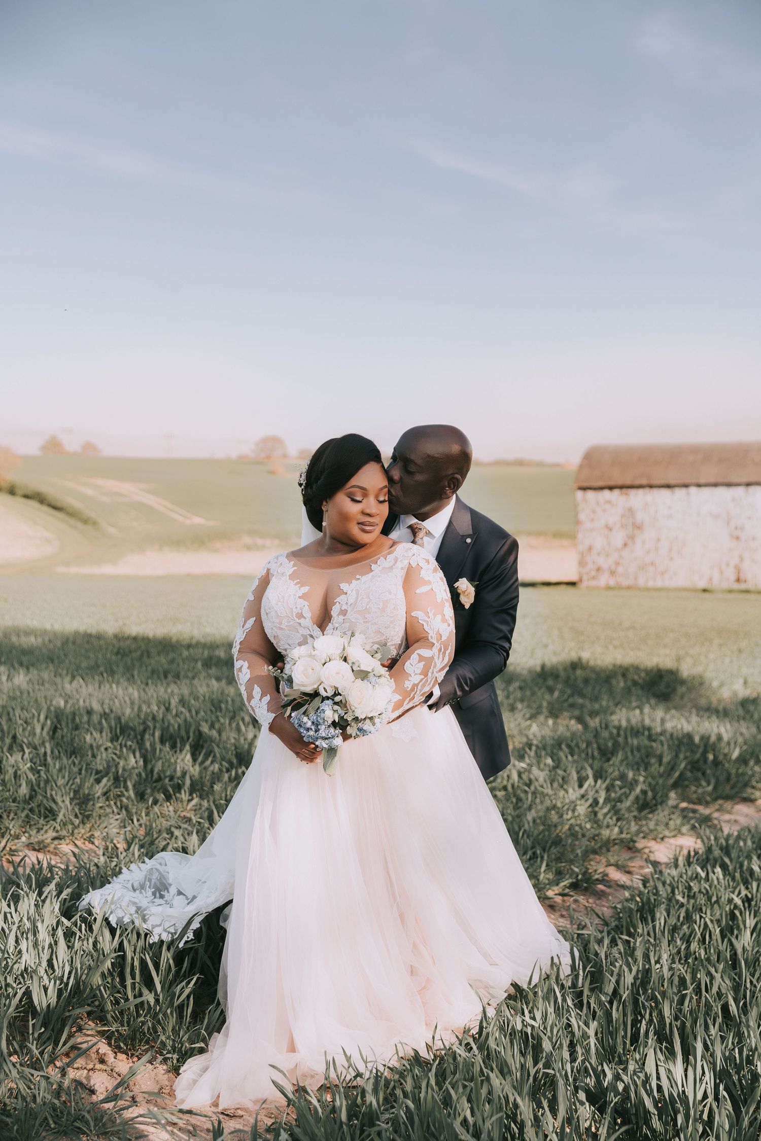 A beautiful outdoor wedding photo featuring a couple in formal attire standing in a grassy meadow.