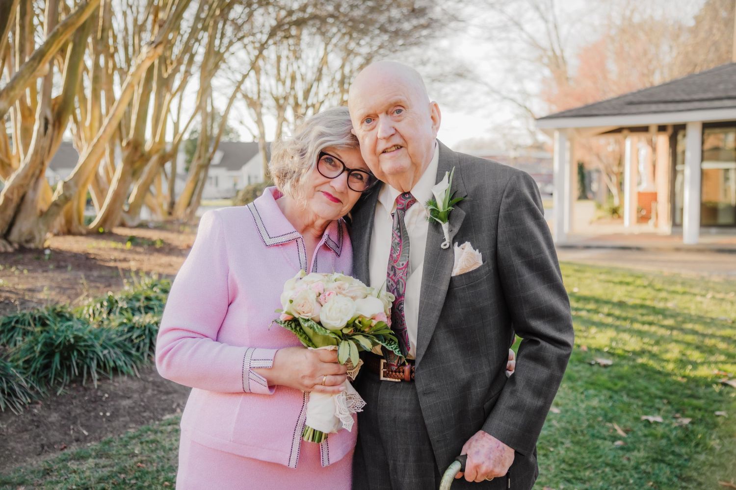 Sweet couple in formal attire sharing a tender moment in a garden setting.
