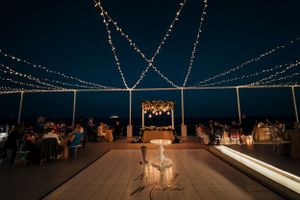 Evening wedding reception setup with string lights creating a magical canopy over an outdoor terrace.