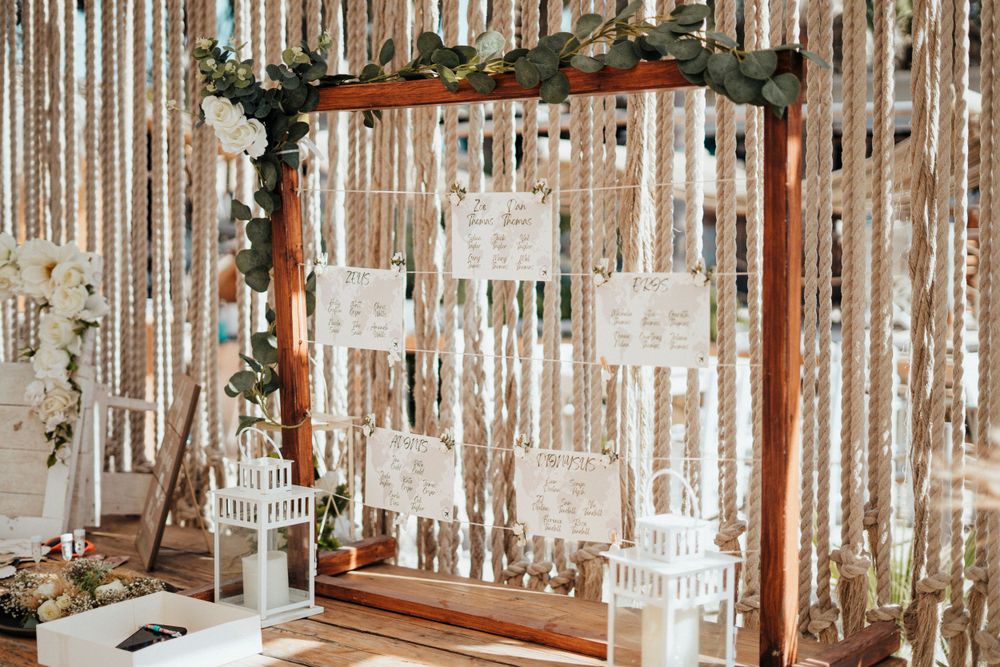 Wedding decor featuring wooden arch with hanging decorations and white streamers creating a romantic backdrop.
