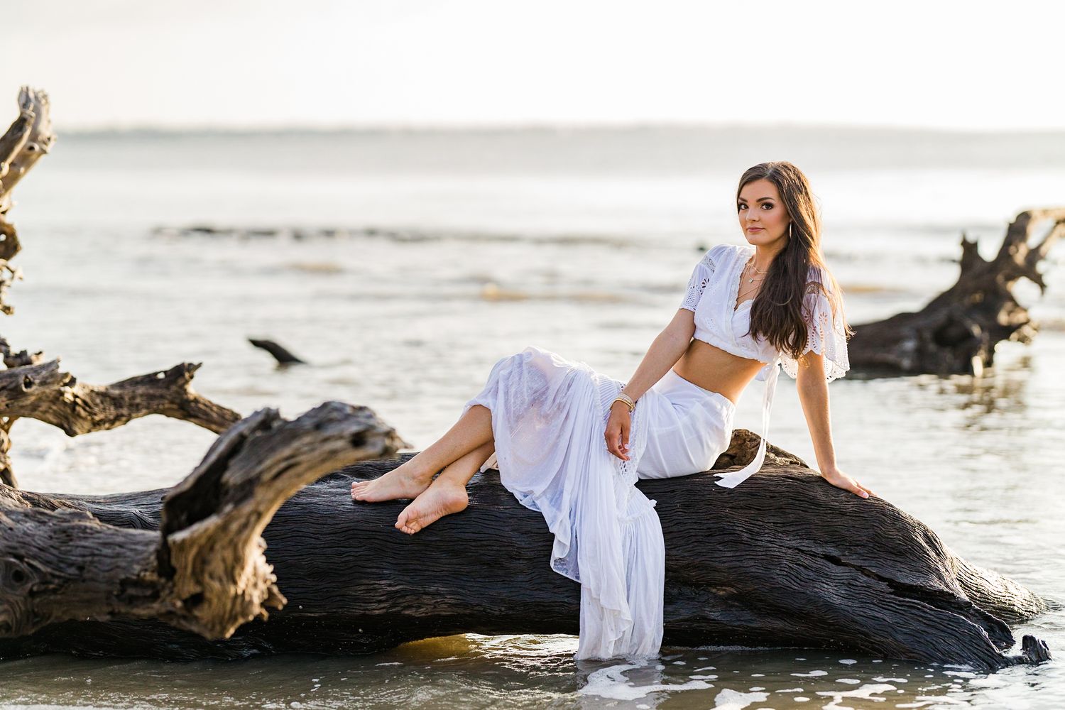 senior girl in white dress on driftwood beach