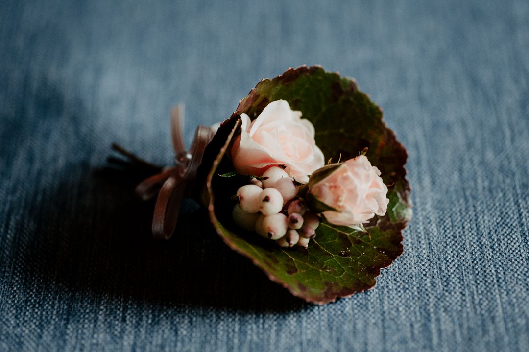 Delicate pink floral arrangement with green leaves on blue textured fabric.