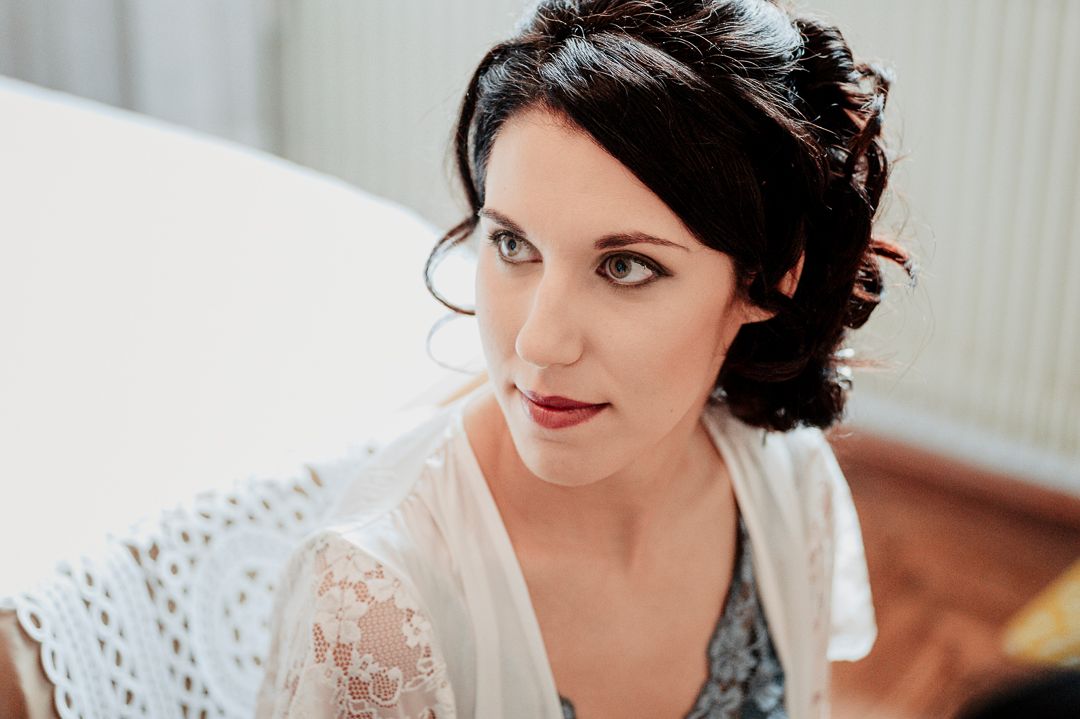 Close up portrait of bride in white lace robe with elegant makeup and hairstyle.