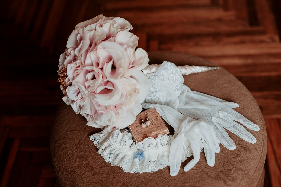 Wedding accessories including pink bouquet, white lace gloves, and decorative details.
