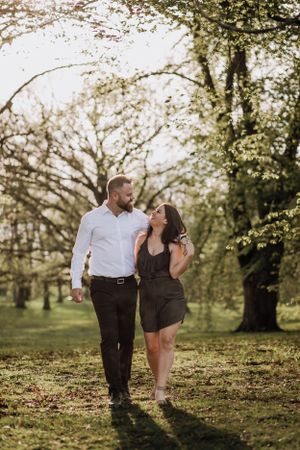 A couple walks together through a sunlit park during golden hour.