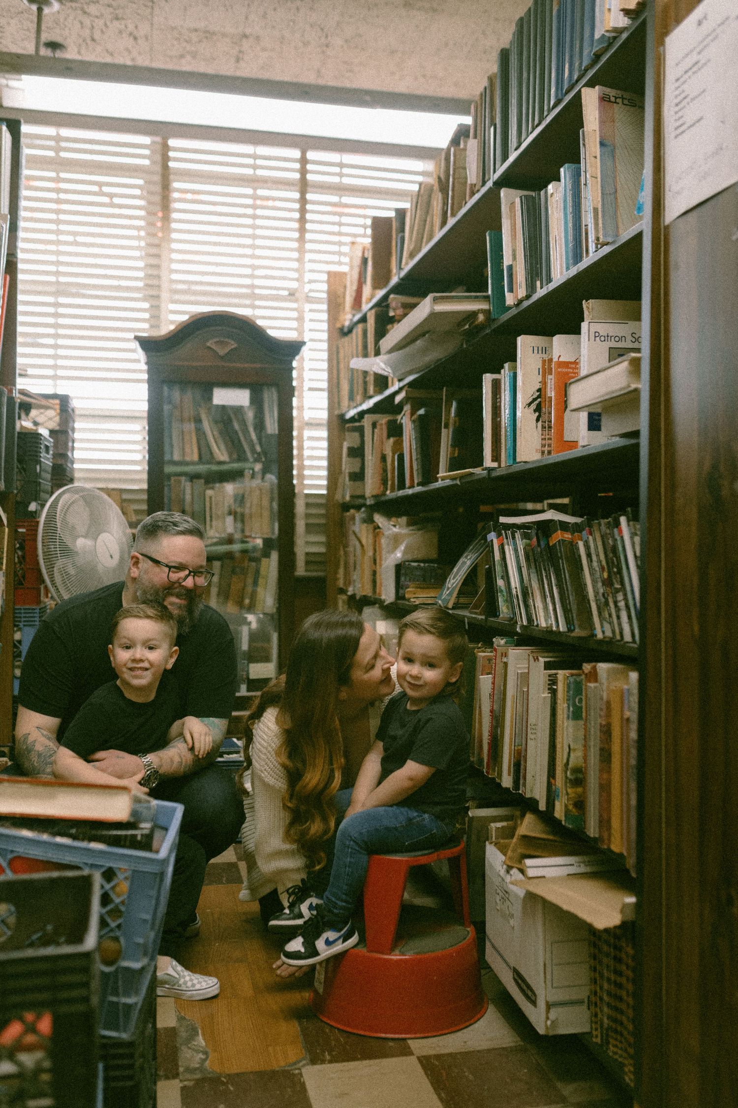 Reading together in a cozy corner of a library surrounded by towering bookshelves.