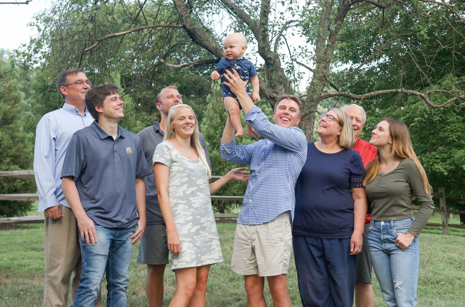 Candid outdoor family gathering with multiple generations sharing joyful moments together.