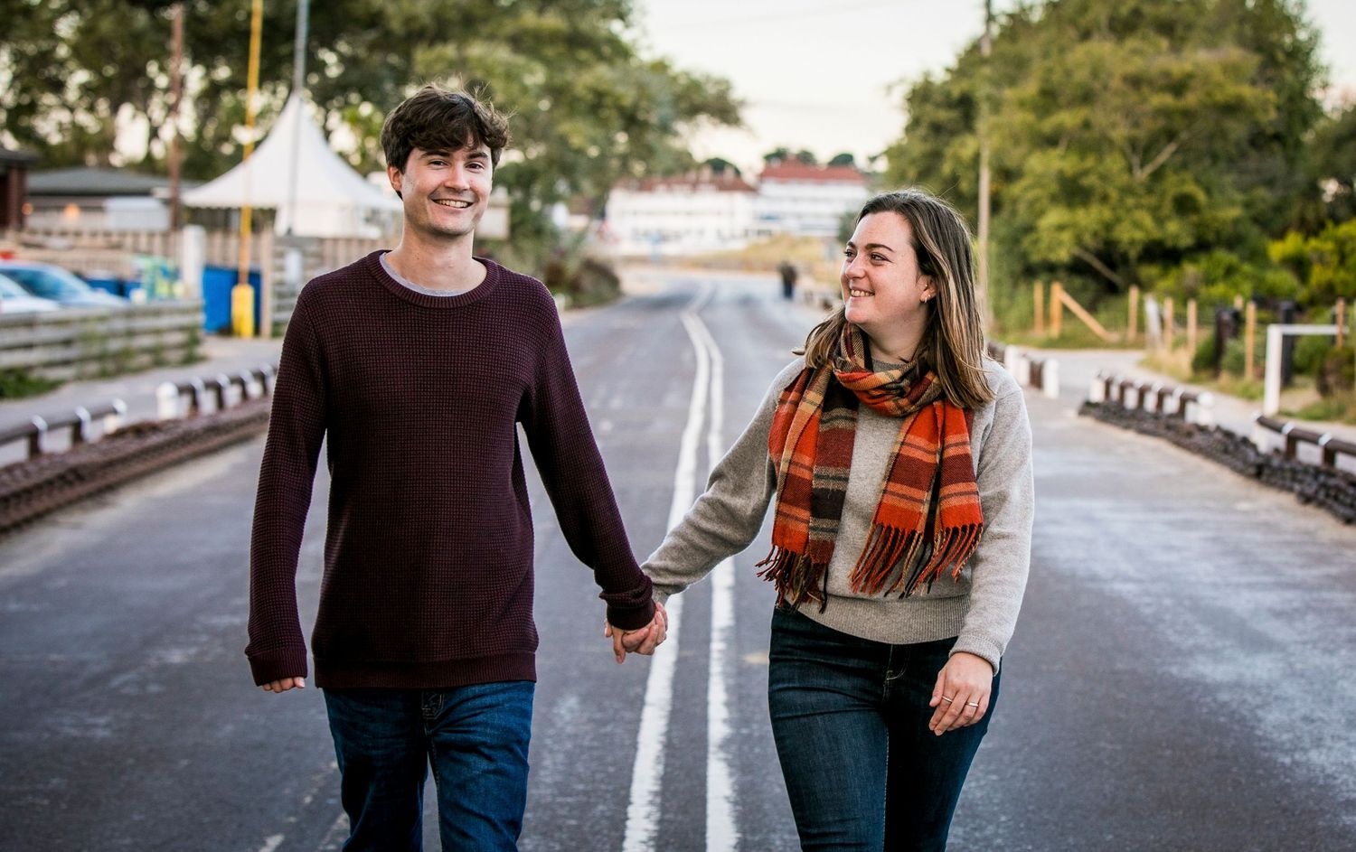 A couple walks together on a paved road wearing coordinated casual outfits.