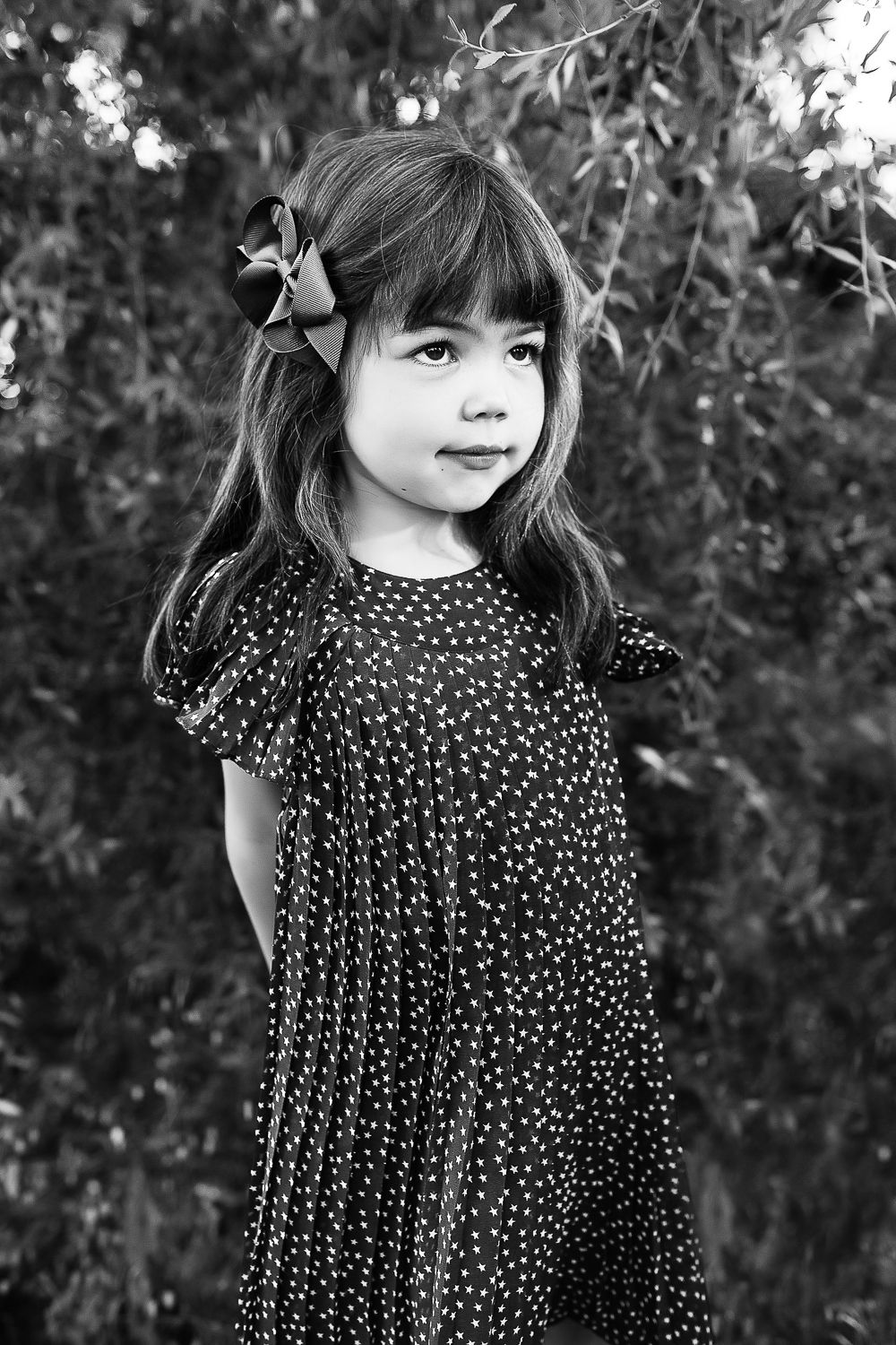 Black and white portrait series of a child in a polka dot dress outdoors.