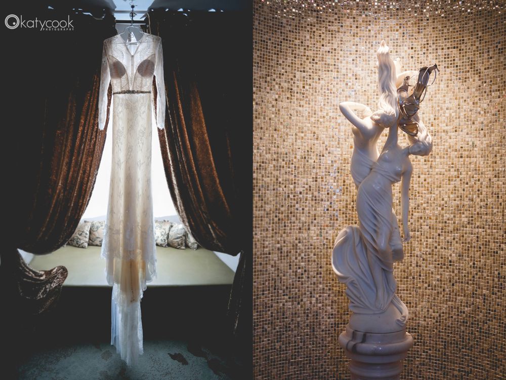 Wedding dress hanging in window light next to decorative statue.