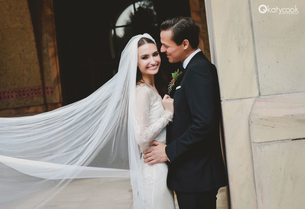 Intimate wedding portrait with flowing veil against stone archway.