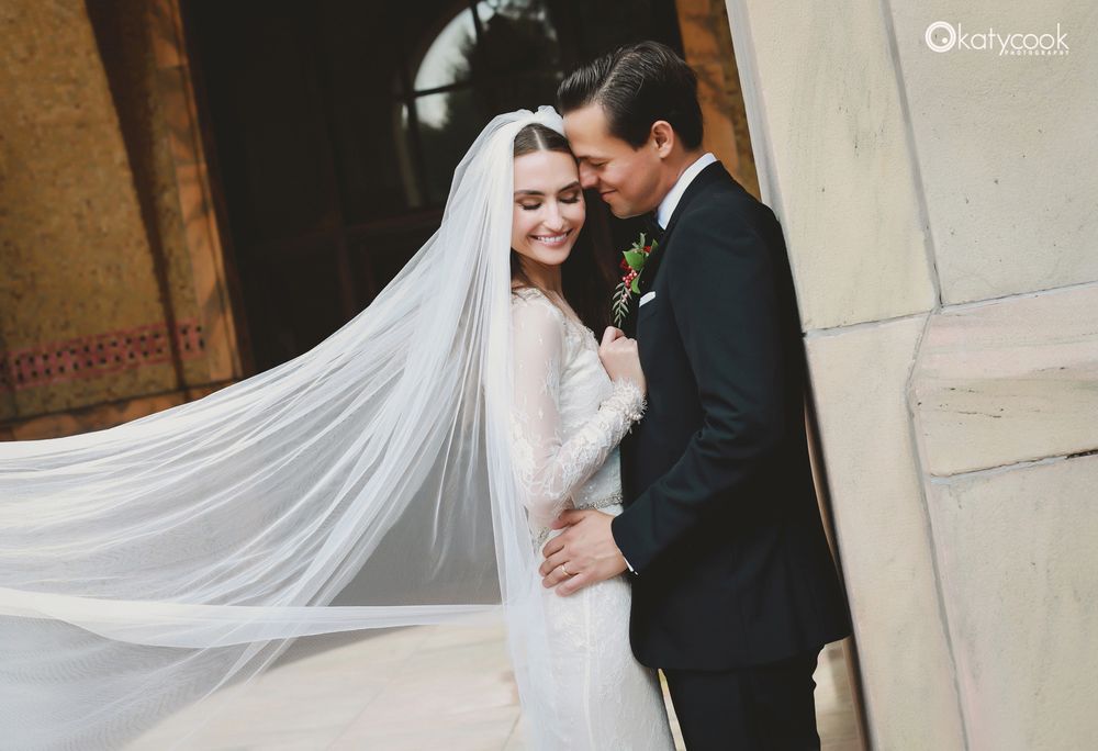 Romantic wedding moment captured with dramatic veil and classic architecture.