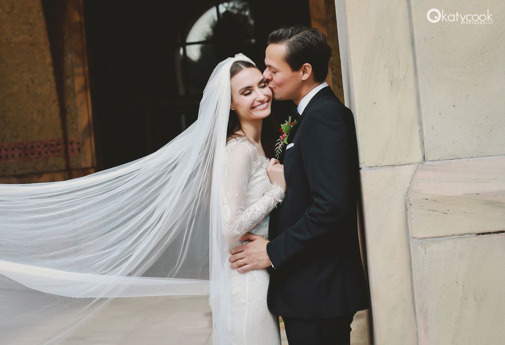 Tender wedding moment captured with elegant veil and classic architectural details.