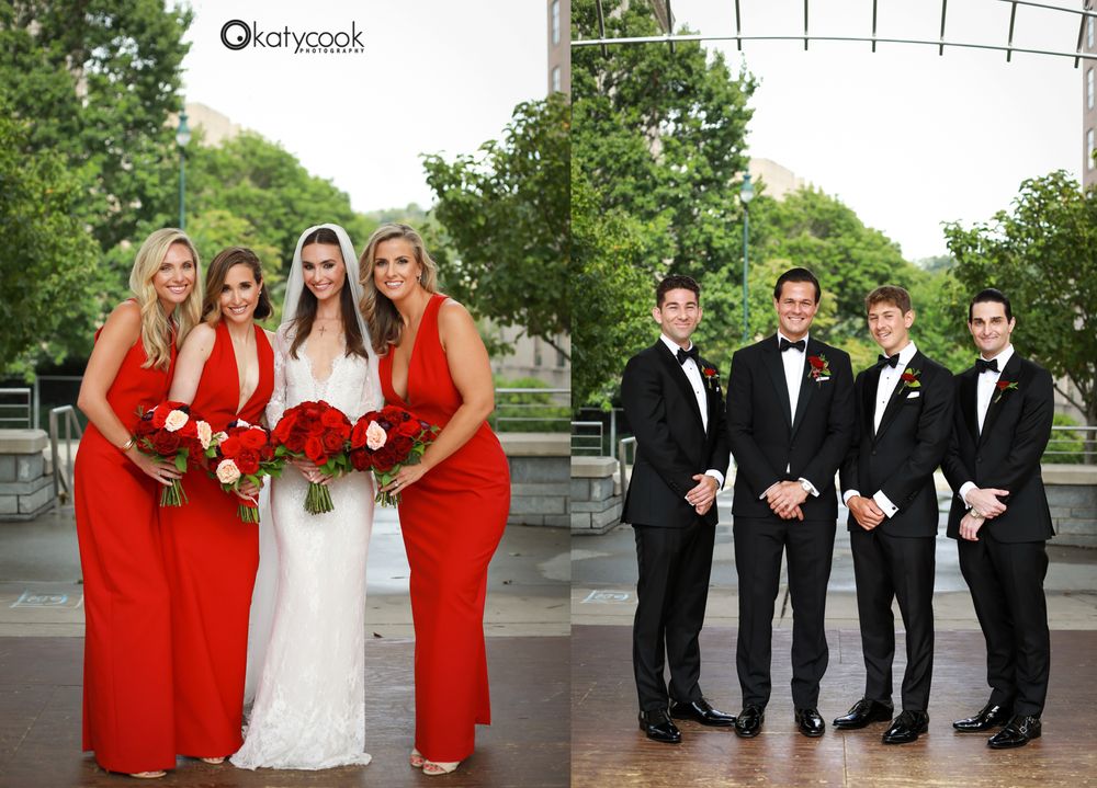 Wedding party in red dresses and black tuxedos poses outdoors.