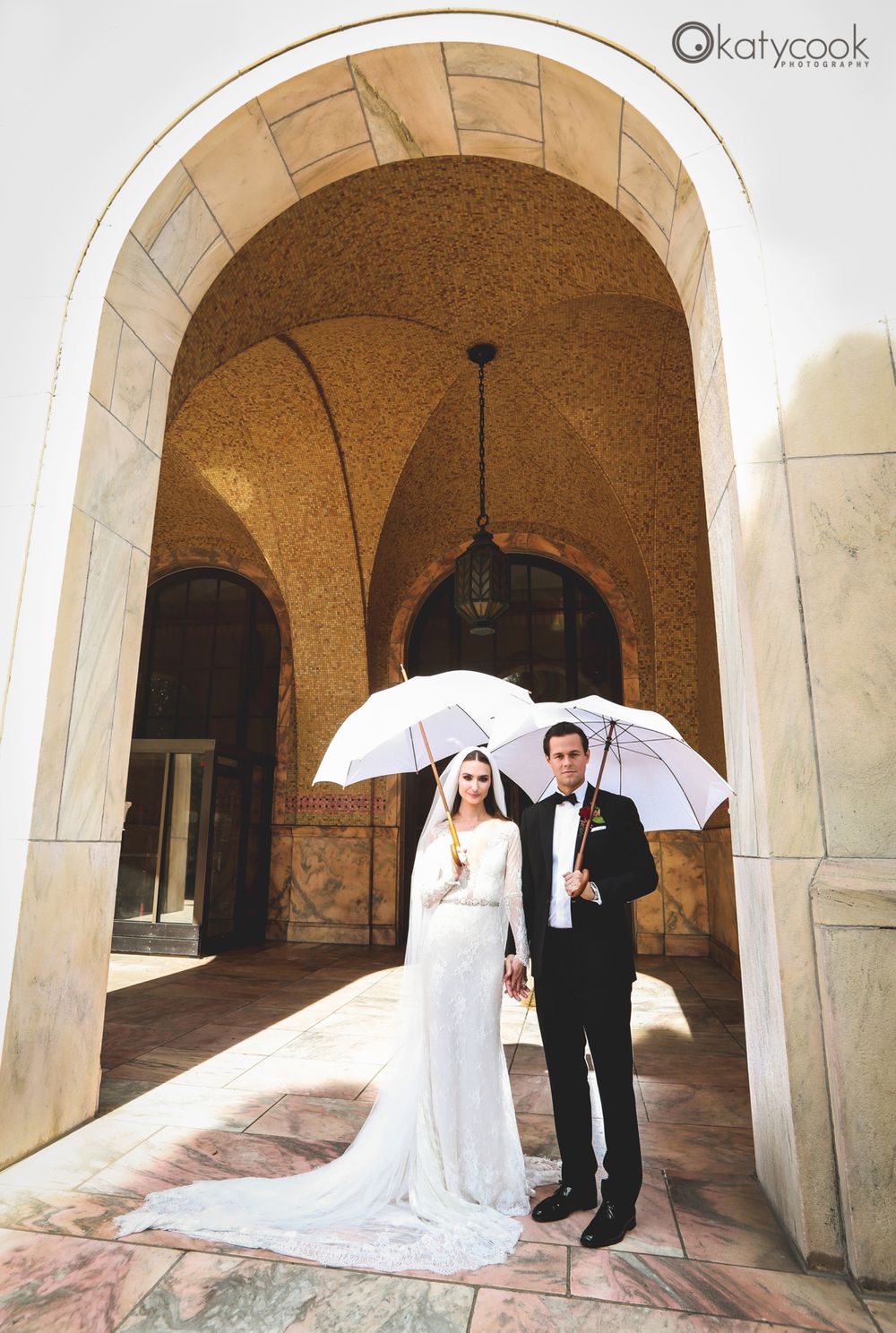 Elegant wedding photos under stone archways with white parasol accents.