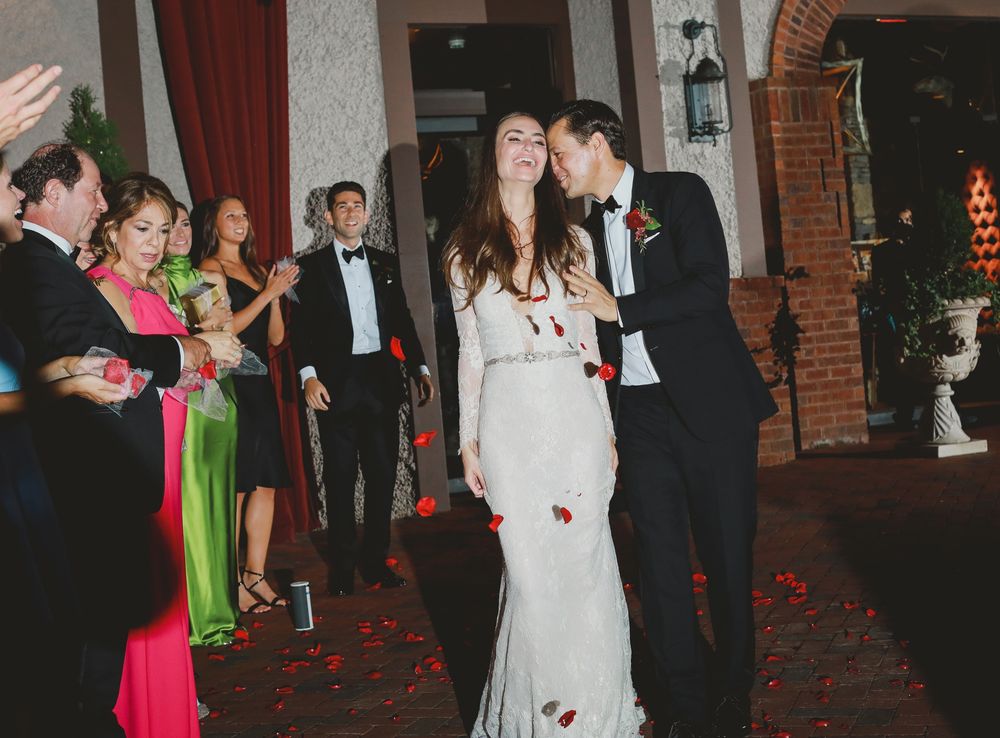 Wedding celebration in a vintage brick venue with couples dancing on a rose petal-strewn floor.