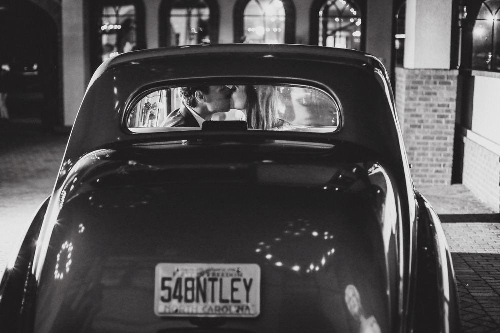 Vintage black car exterior parked at night outside a brick building.