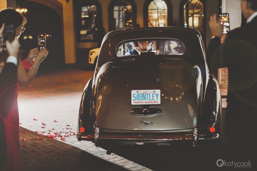 Classic car with vintage license plate parked at night on brick pavement.