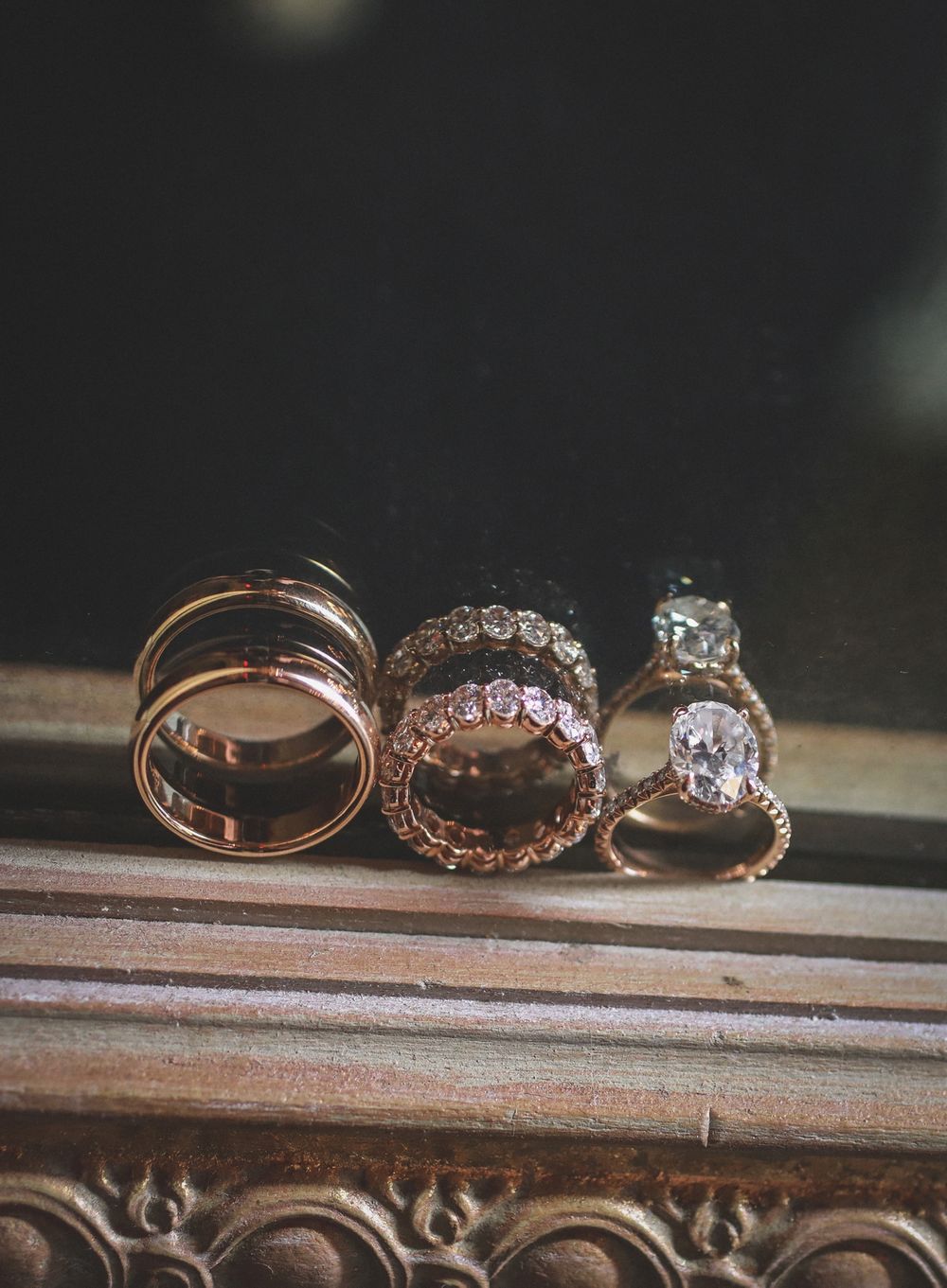 Collection of diamond and rose gold wedding rings displayed on wooden surface.