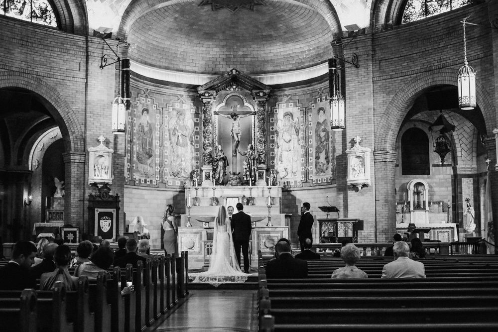 Black and white photo of traditional church wedding ceremony with ornate architecture.